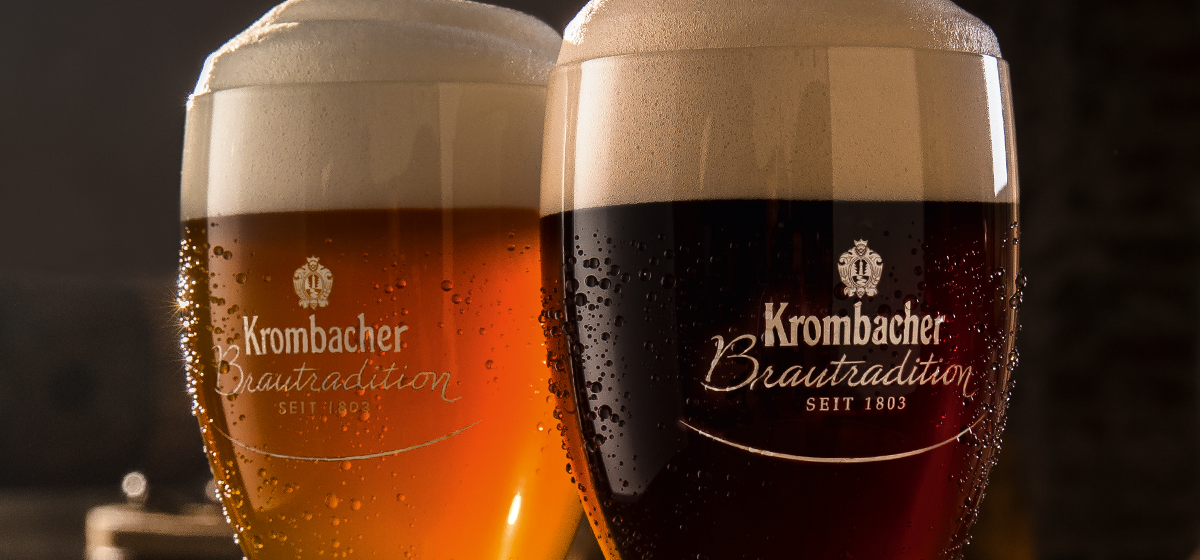 Zwei Gläser Bier stehen nebeneinander, eines davon ist ein Kellerbier, das andere ein Dunkelbier. Auf den Gläsern steht Krombacher Brautradition seit 1803.